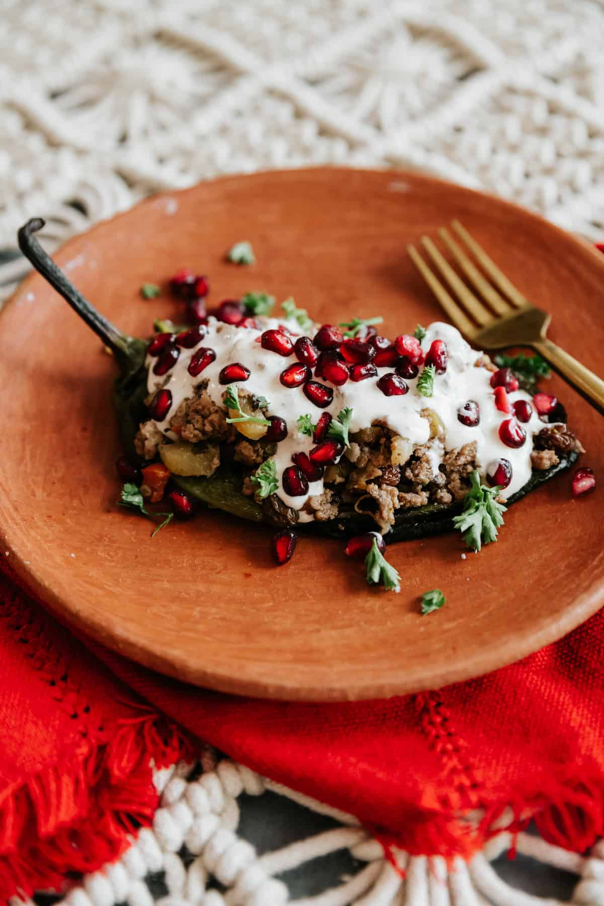 Os *chiles en nogada* consistem em pimentas *poblano* assadas, 
              recheadas com um *picadillo* agridoce feito de carne moída, frutas e especiarias aromáticas, 
              cobertas por um molho aveludado de nozes, sementes de romã e salsinha.