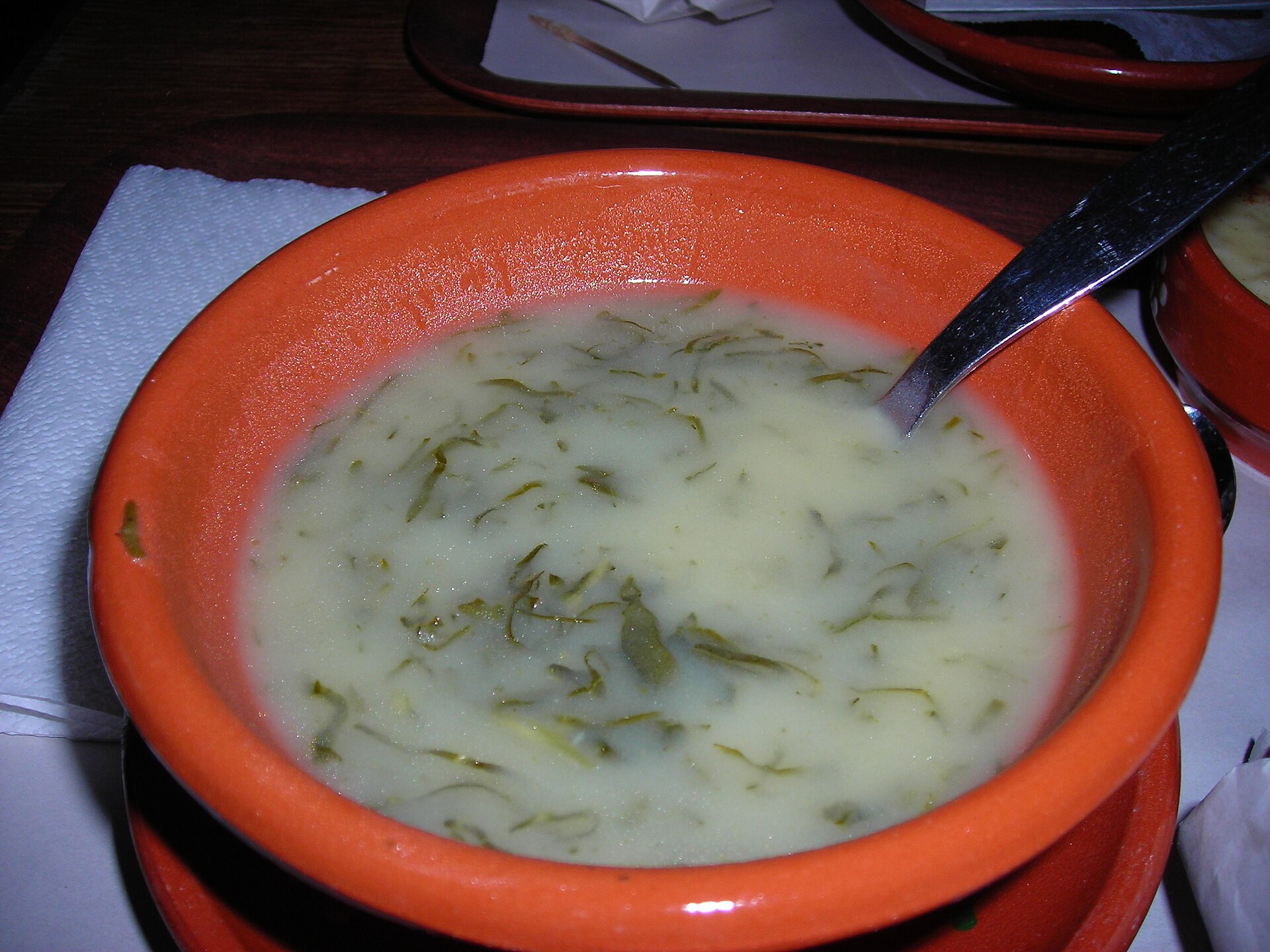 Caldo verde com tiras de couve, servido em uma tigela de barro.