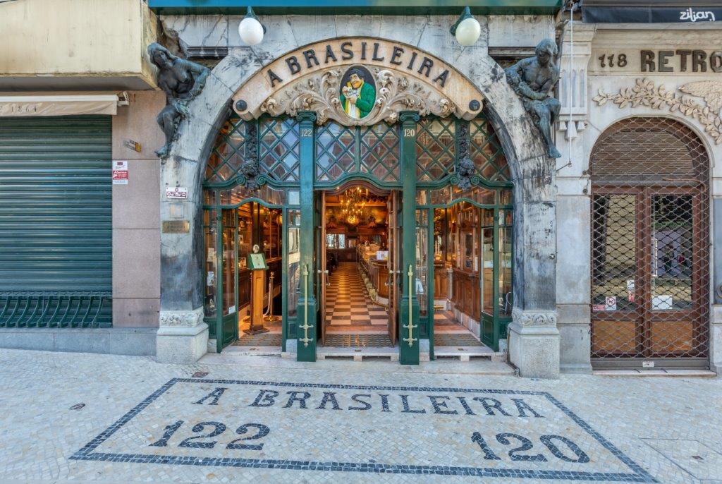 Entrada do café A Brasileira, no Chiado, com portas verdes e calçada portuguesa.